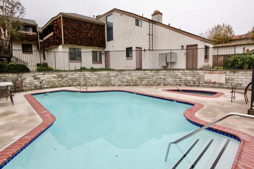 THIS IMAGE SHOWS THE SWIMMING POOL IN LA HABRA, THAT SHOWS THE CHAIRS, PLANTS NEARBY HOMES