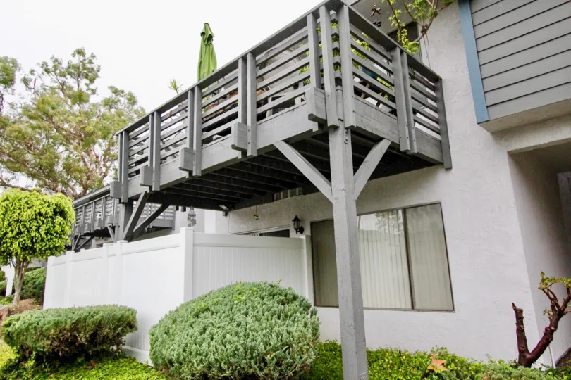 Closed umbrella and flower pots is placed on the balcony of the villa in Woodlake Village with cutted bushes below to it