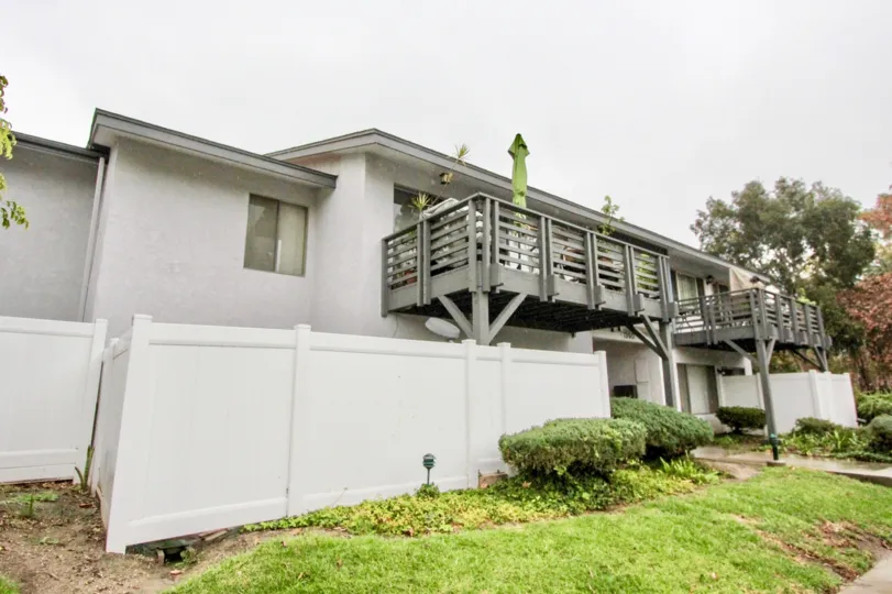 a rainy day in the woodlake village with a house that has bal cony and white walls and garden around