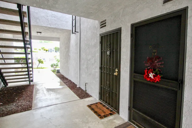 a pleasant day in the woodlake village with a house that has numbered as 97 and flower decrated in the door steps in left side