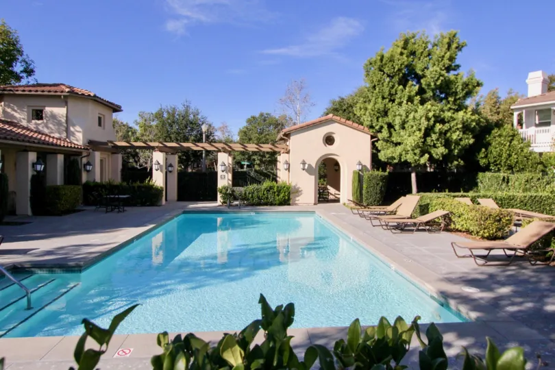 A pool with chairs and tan building around it at the Atherton Glen community in Ladera Ranch, California.