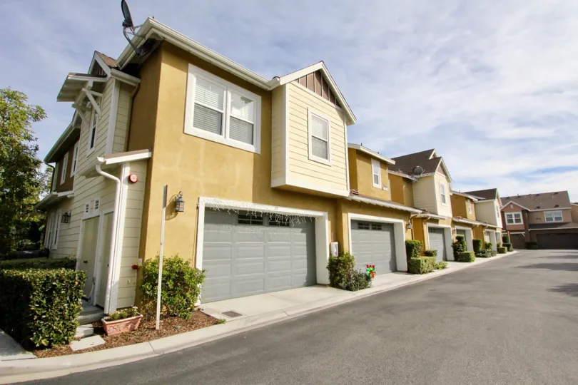 A row of bright yellow homes with garages on a sunny day in the Branches community in Ladera Ranch, CA