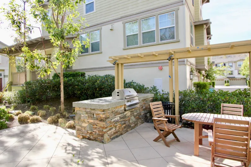A view of the back of a townhome in Briar Rose Community in Ladera Ranch, California. This view is of the patio, grill and outdoor tables and chairs.