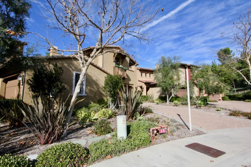 THIS Image represents the house in the community of Castellina which have the lot of plants, trees and the path way to the house placed in the city of Ladera Ranch