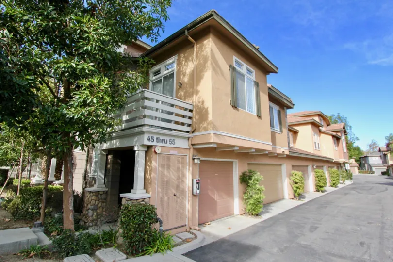 A SIGHT OF A BEAUTIFUL APARTMENT WITH THE CONTRAST OF BROWN & PEACH COLOR LOCATED BY THE ROAD SIDE ON A SUNNY DAY