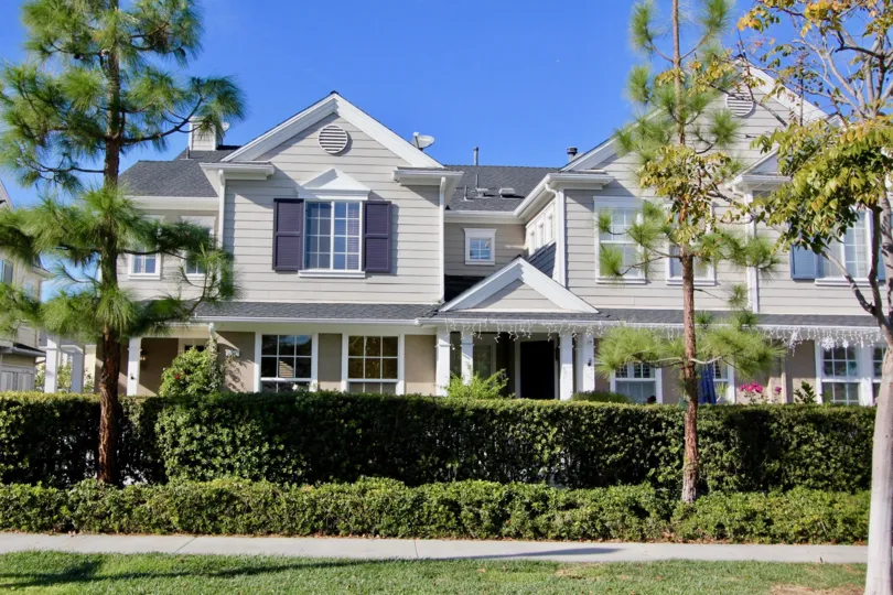 A sunny day at a Charleston Place duplex with christmas lights along the roof and bushes and trees in front of it