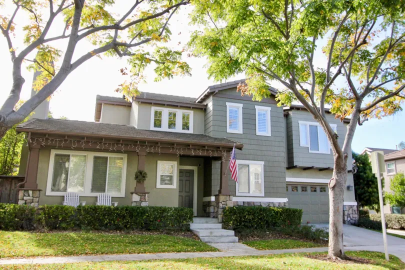 A sunny day on a grey home with trees in the yard at Trails community in Ladera Ranch, California.