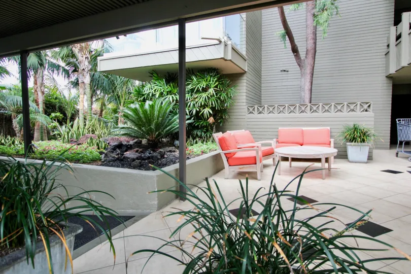 Outdoor patio with tile flooring, tropical foliage, and orange patio furniture in Laguna Lido