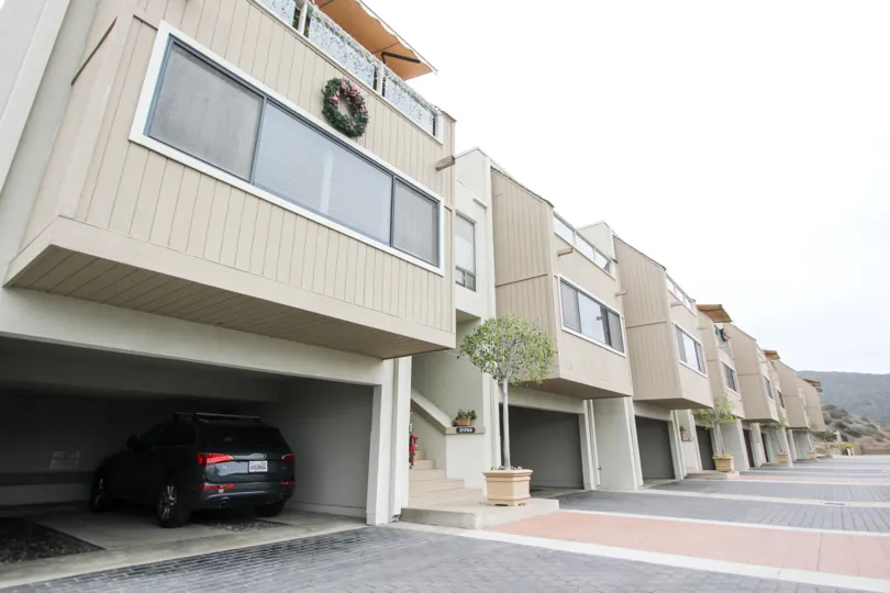 A day in the Laguna Ocean Vista with modern apartments and a vehicle.