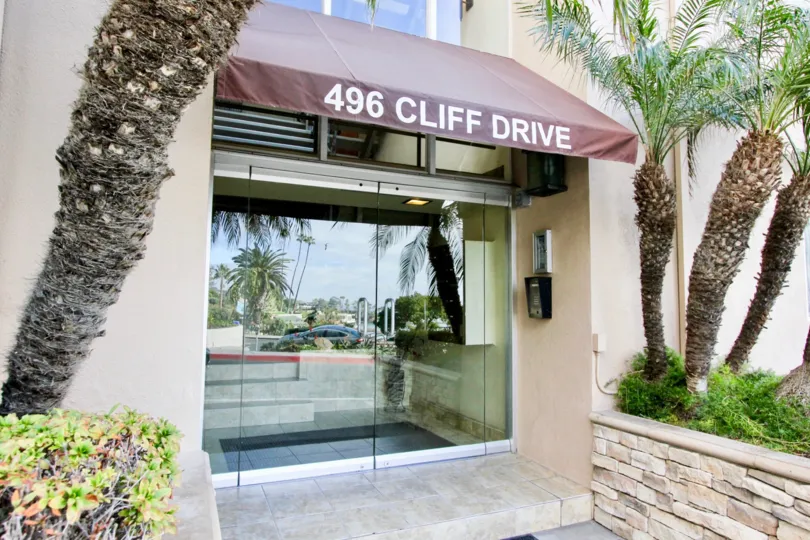 A sunny day in the Ocean Cliff Manors with the entrance of a building and sign.
