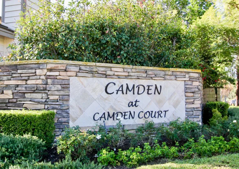 A stone wall with a sign informs visitors they have arrived at Camden at Camden Court