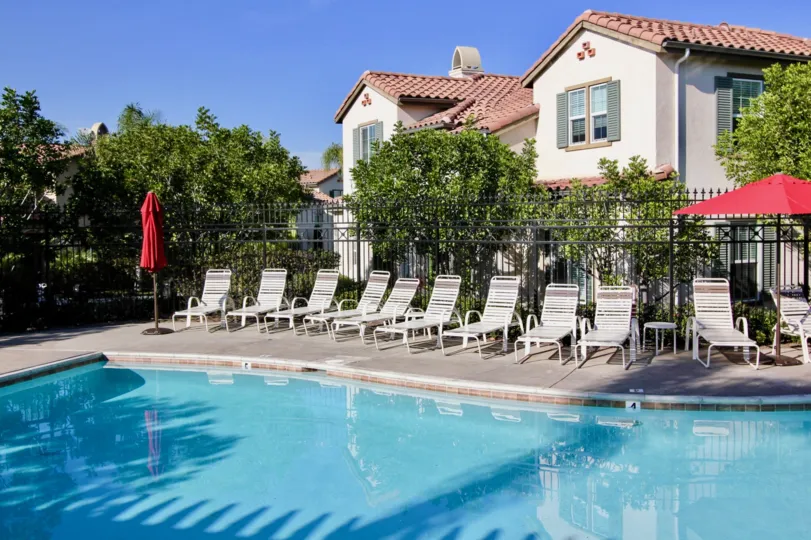 Sun tan chairs with red umbrella and swimming pool in Cornerstone.