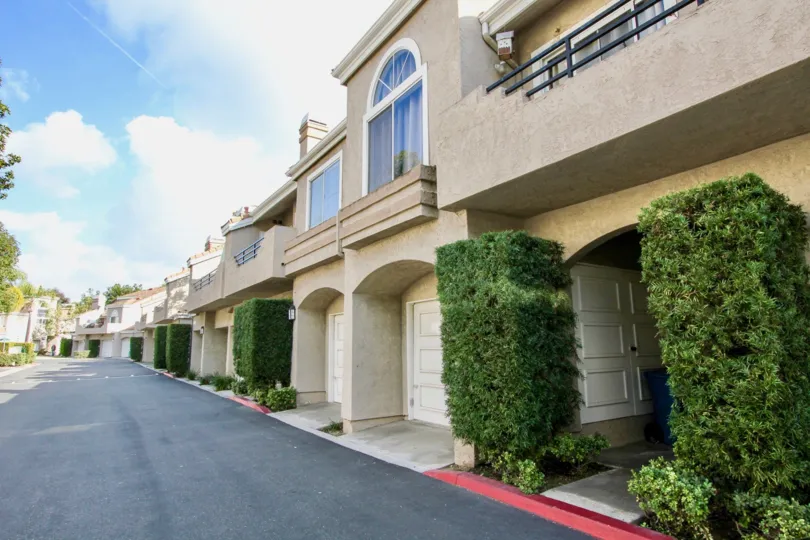 A two-storey townhouses with arched entrance and tall shrubs in the Expressions community.