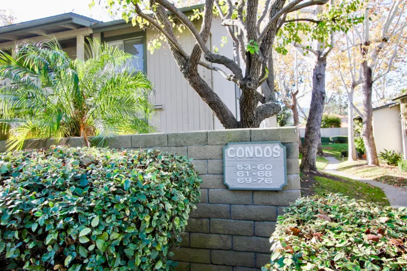 THE FLATS IN THE HILLHURST CONDOS WITH THE CONDOS BOARD, PLANTS, TREES, PATHWAY