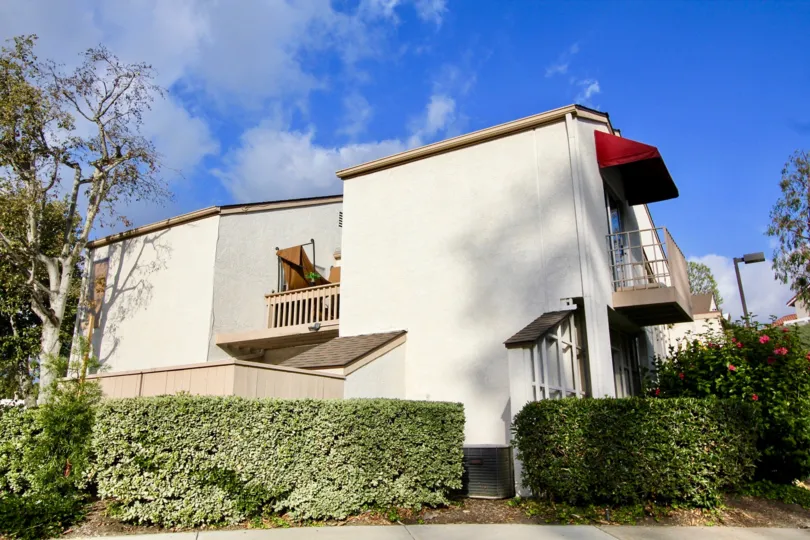 Shrubs wall with red color balcony and trees in Vista Del Cerro.