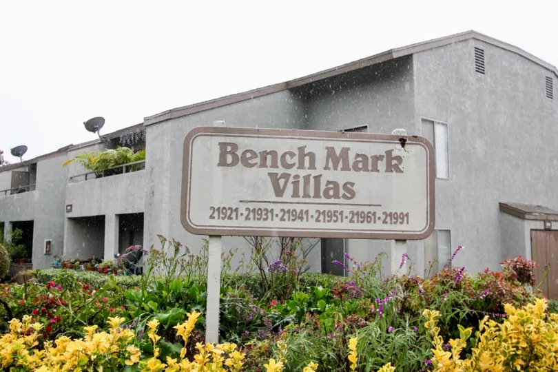 A gray building in the Bench Mark Villas community in Lake Forest, CA with yellow and purple flowers