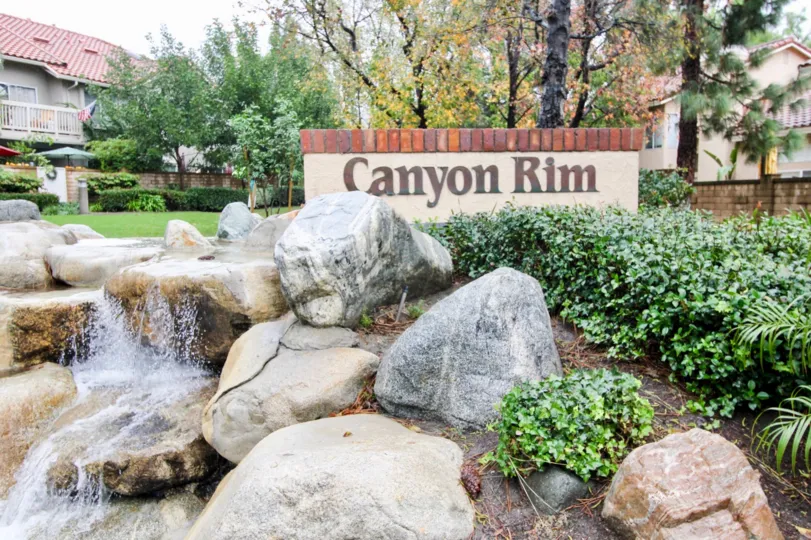 A sunny day in the area of Canyon Rim, trees, roof, condo, rocks, waterfall, sign