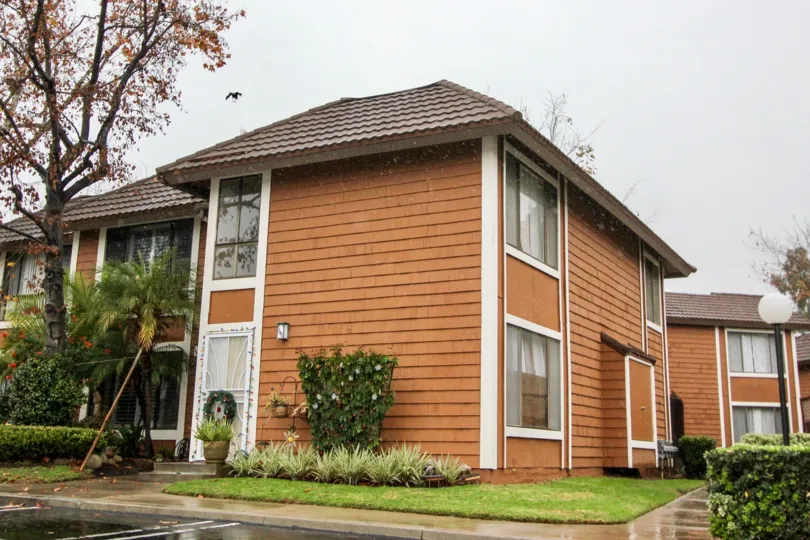 A rainy day by a Cedar Glen complex with trees on one side and bushes and grass on the other