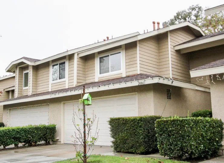 Drive way of a Heatherview home in Lake Forest CA, with a little green bird house on a tree