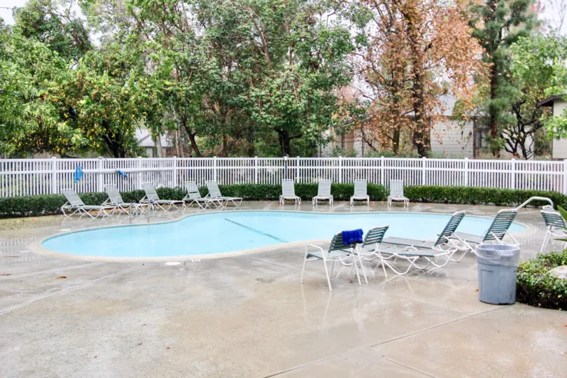 A blue color swimming pool in the Pheasant Creek with some chairs.