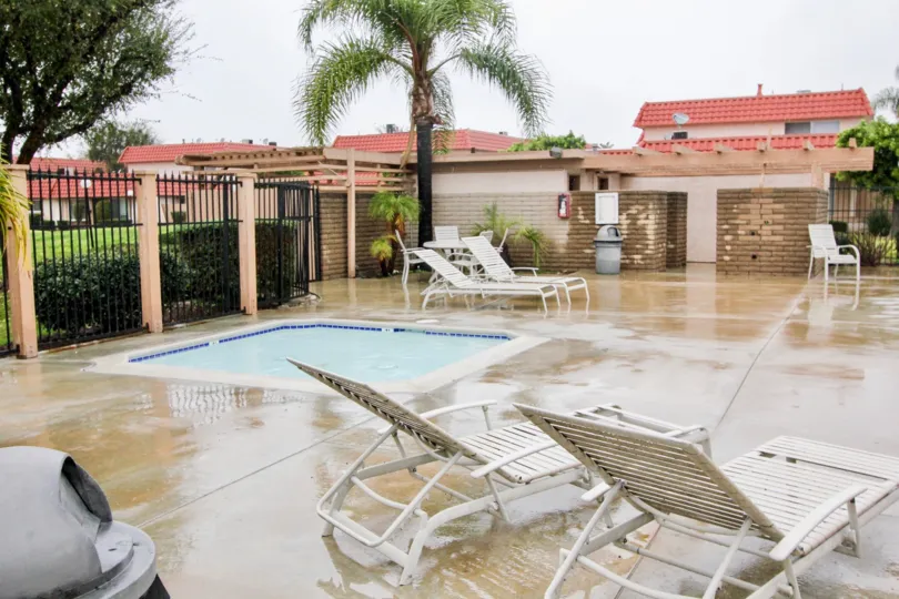 A small swimming pool in the Rancho Viejo Condos I with some chairs.