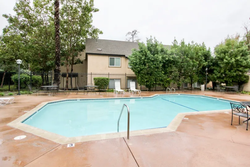 There are some chairs nearby a swimming pool at Serrano Creek Villas