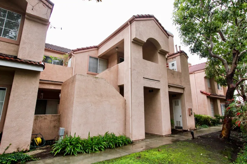 Many tan homes with a wet sidewalk and ground in Serrano Sandcastle community in Lake Forest, California.