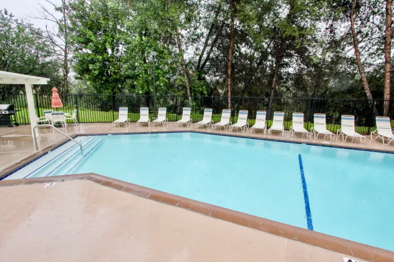 A SIGHT OF BEAUTIFUL SWIMMING POOL OF A BUILDING SURROUNDED BY HUGE GREEN AREA