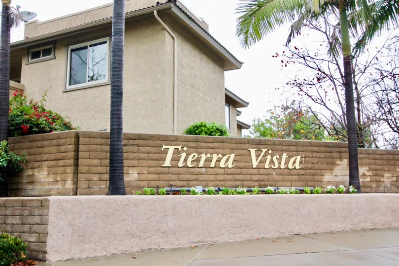 A sign is on the wall nearby a palm tree in the Tierra Vista.
