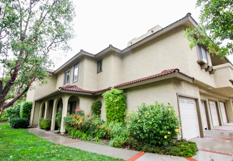 A large bush with yellow flower on it sits near a townhome in the Tierra Vista community