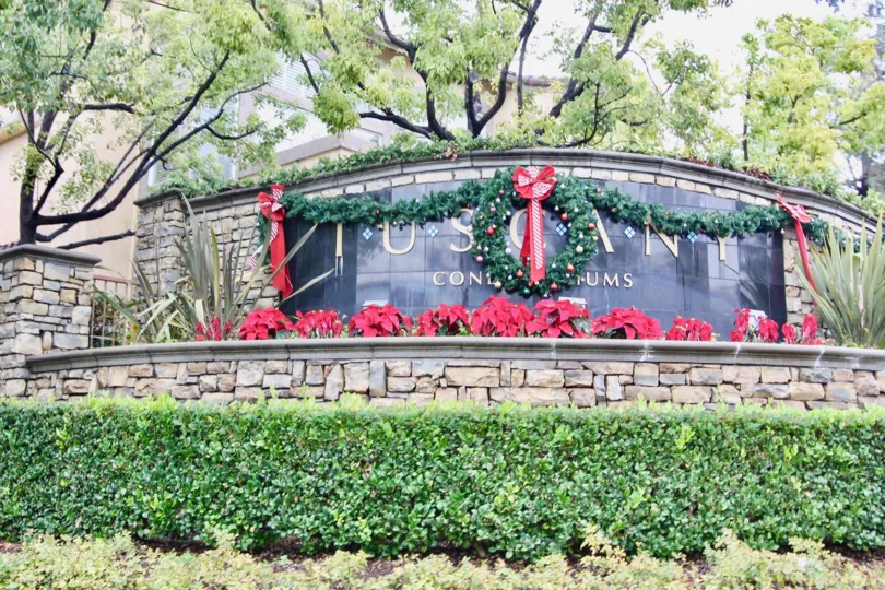 The entrance sign to Tuscany Condominiums at Foothill Ranch, decorated with a Christmas wreath and poinsettias.