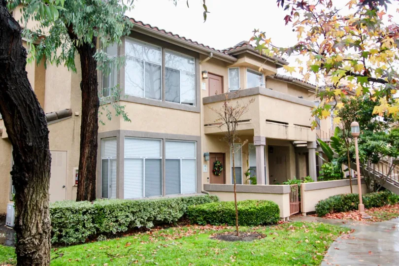 A apartment complex with bushes and trees around the building in Tuscany at Foothill Ranch community in Lake Forest, California.