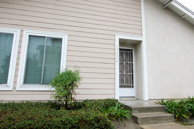 A white gate covers a screen door of a townhome in Viejo West condso