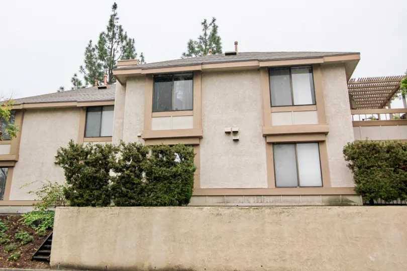 A front view of a home in Lake Forest, California. Includes several bushes, trees, and a view of the porch.