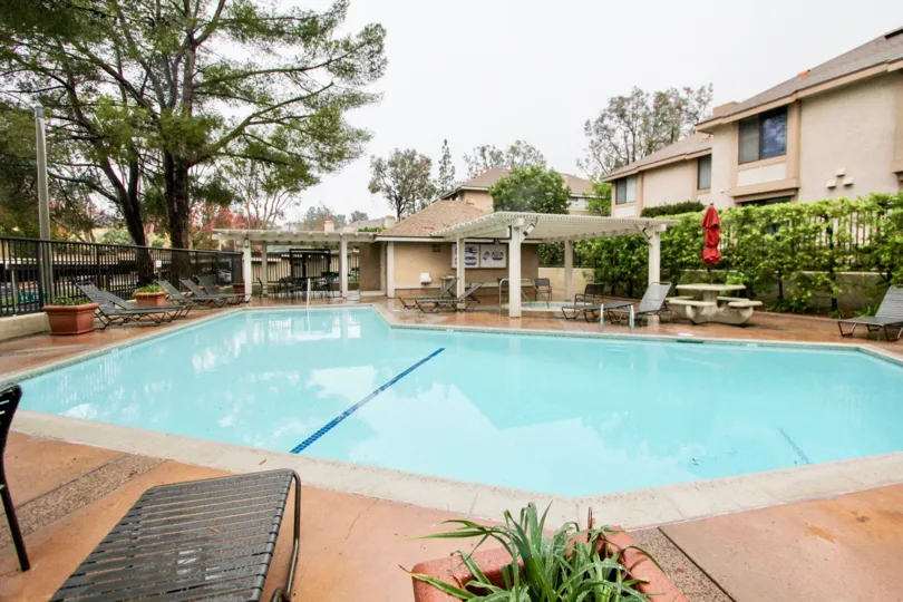 A pool in the White Oak community in Lake Forest California, surrounded by foliage and picnic tables.
