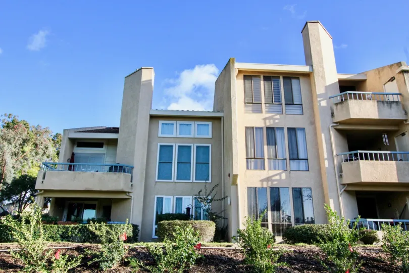 A three floor apartment and has white color with sun glass windows at the morning sun light.