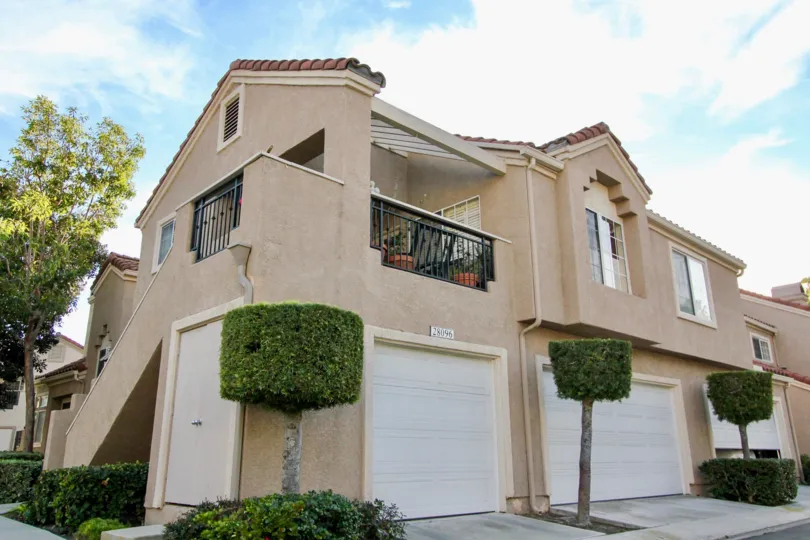 Small trimmed trees stand next to garage doors of the Palm Garden units in Mission Viejo, California.