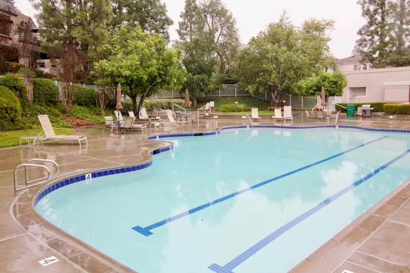 A rainy day at a public pool in Mission Viejo, California, with several empty lounge chairs.