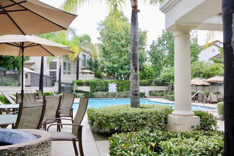 Swimming pool with table and chairs with umbrella in Greystone Califia.