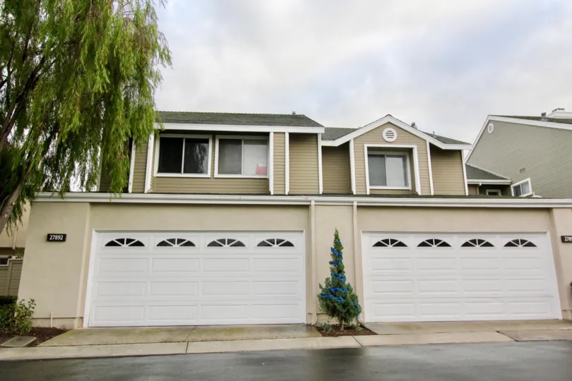 A cloudy day over a modern house with duel garages and a clean driveway.