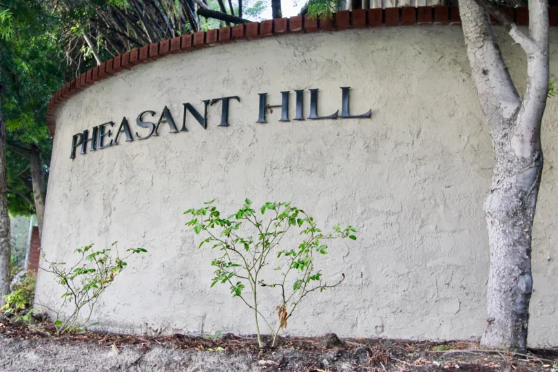 a pleasant day in the pheasant hill with a wall that has a treein front and named its community in it
