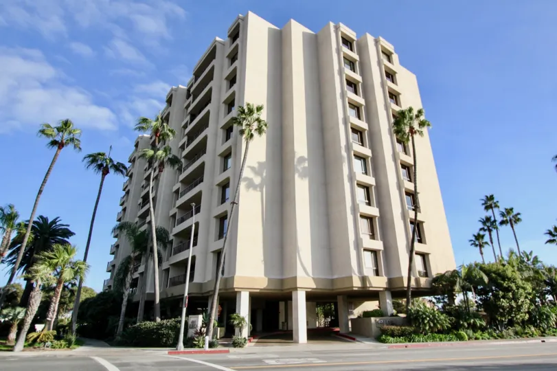 A sunny day in the Lido Park Place with a huge apartment and palm trees.