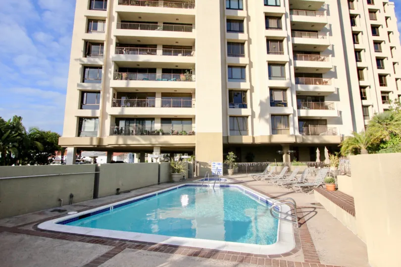 a sunny day in the lido park place with atall building that has clear blue swiming pool in it