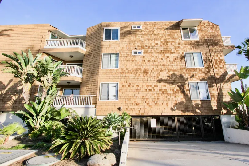 A SUNNY DAY IN THE BALBOA PENINSULA WITH A BUILDING THAT HAS BRICK LIKE WALLS AND HAS STEEL GATE OUTSIDE