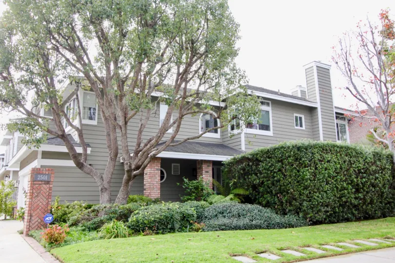 a warm day in the beacon court with a large house that has garden in front and a tree that spreads
