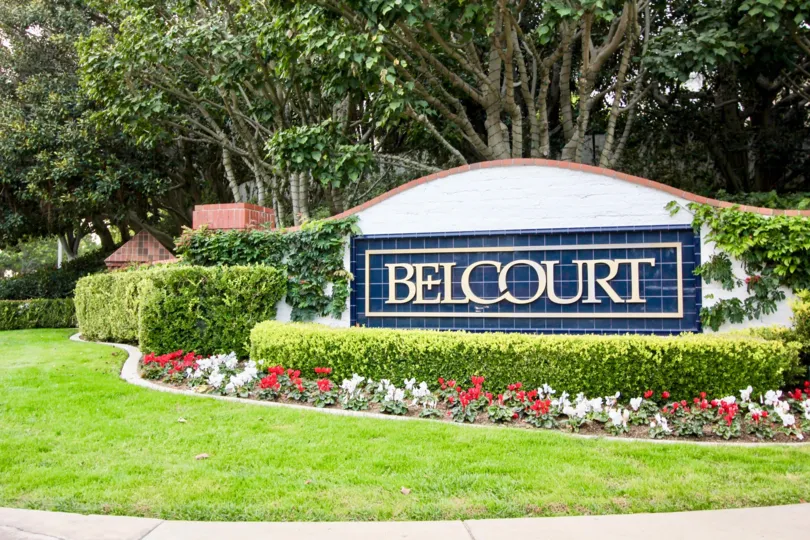 A beautiful garden surrounding the welcoming sign for the Belcourt Towne Collection in Newport Beach, CA