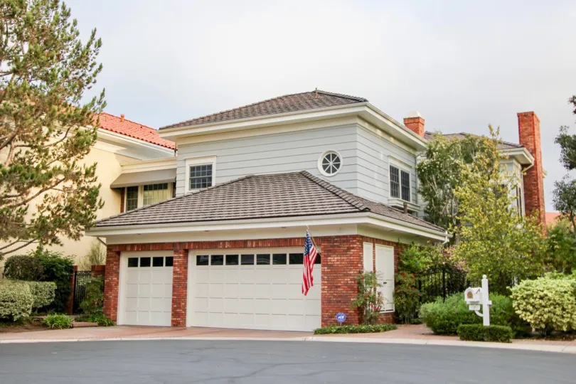 THE VILLAS IN THE BELCOURT TOWNE COLLECTION WITH THE FLAG, ROADSIDE, PLANTS, TREES, STEEL GATE