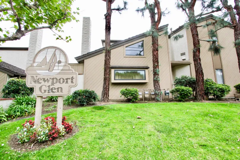 THE SIDE STRUCTURE OF THE HOME IN THE NEWPORT GLEN WITH THE NAME BOARD, MOTOR, PLANTS, TREES, LAWN