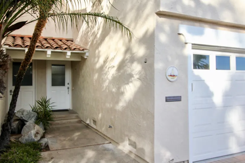 a warm day in the newport beach with house that has front of tree in stone, slide door