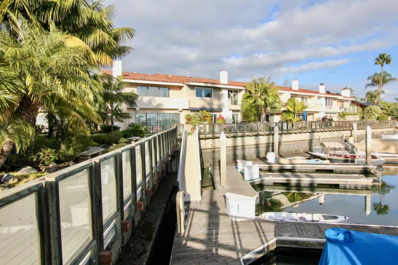 A beautiful day in the Newport Marina Villas with a pond and trees.